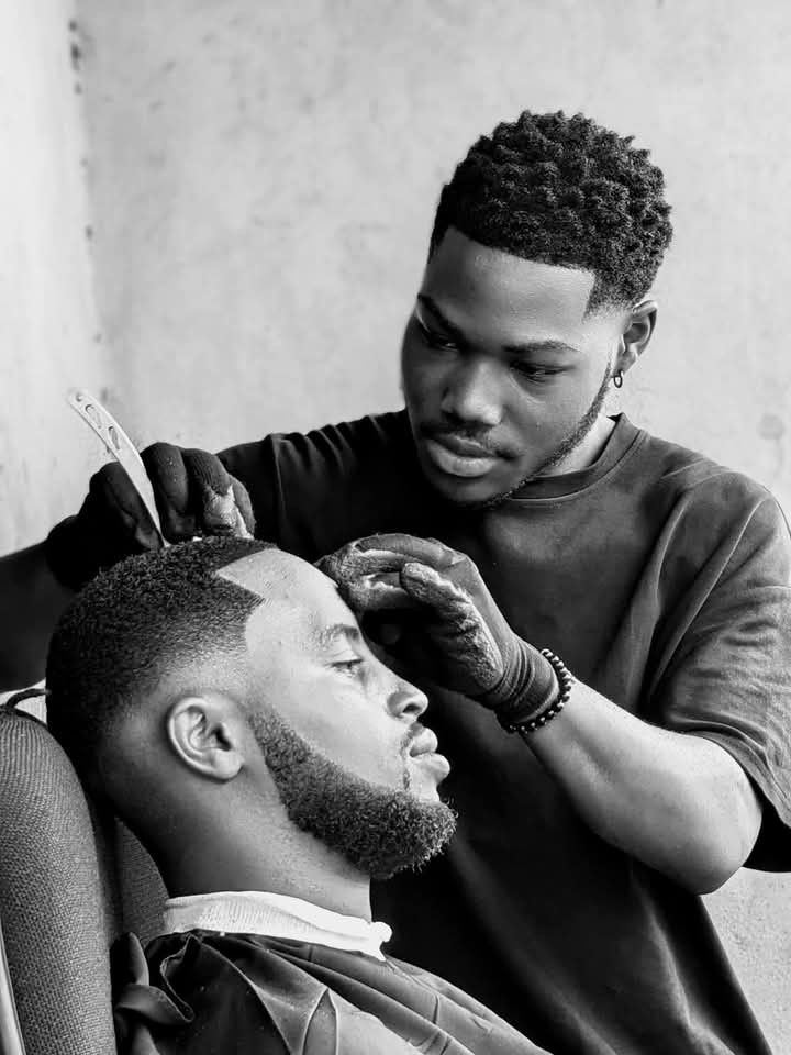 Master barber finishing a razor lineup in black and white