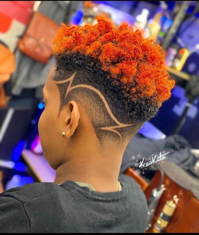 Bright orange curls with a geometric design shaved into the fade